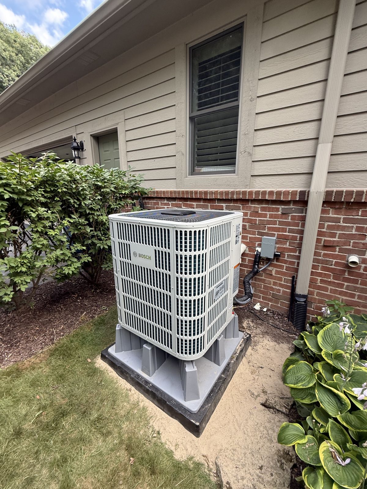 A Bosch outdoor unit installed by Oak Grove on a new pad