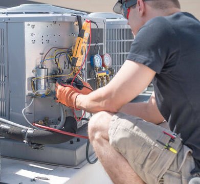 Technician performing HVAC repair on a commercial rooftop unit using diagnostic tools and gauges.