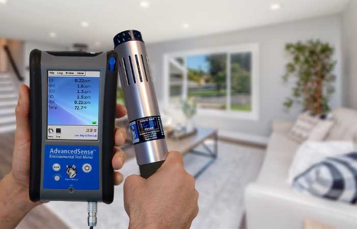 Technician holding an indoor air quality testing device inside a modern living room to measure pollutants and ensure healthy indoor air.
