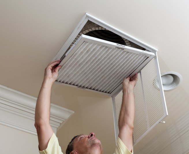 Technician replacing a ceiling air filter to improve indoor air quality and HVAC airflow efficiency.